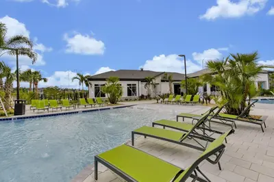 a swimming pool with green chairs and a building at Top Rated 4BR home in Kissimmee