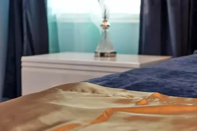 a close up of a bed with a nightstand and a table at 2968 PENELOPE LOOP 10 BED in Kissimmee