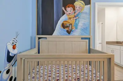 a crib in a room with a painting of a child on a bed at 2968 PENELOPE LOOP 10 BED in Kissimmee