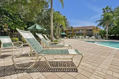 a group of lounge chairs and an umbrella next to a pool at 8460 CRYSTAL COVE LOOP 3BED in Kissimmee