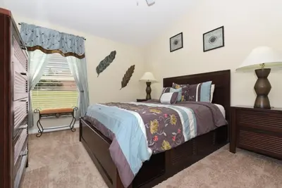 a bedroom with a bed and a dresser and a window at Veranda Palms Villa: Pool, Spa & Game Room in Kissimmee