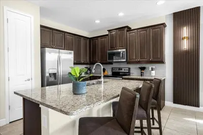 a kitchen with wooden cabinets and a kitchen island with chairs at Awsome 8 Bd 6.5 Ba Sleeps 20 Encore in Orlando