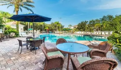 a patio with a table and chairs and a pool at Your Cozy 3 BD Home w Private Hot Tub & BBQ Gril in Kissimmee