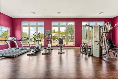 a gym with cardio equipment in a room with pink walls at 12 min da Disney • Casa 3 Q c/ Resort in Kissimmee