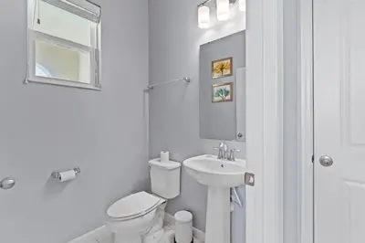 a white bathroom with a toilet and a sink at Compass Bay: 4Q reformados Perto da Disney! in Kissimmee