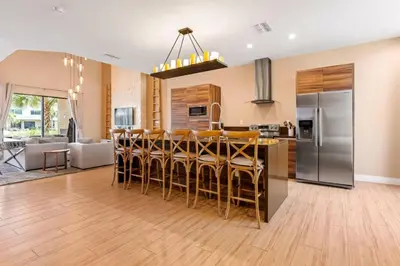 a kitchen with a bar with chairs and a refrigerator at Casa 3 Suítes c/ Churrasco – Perto da Disney in Orlando