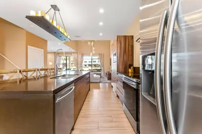 a kitchen with a stainless steel refrigerator and wooden floors at Casa 3 Suítes c/ Churrasco – Perto da Disney in Orlando