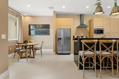 a kitchen with a table and a stainless steel refrigerator at Magic Village Casa com 4 Suítes - 8 min da Disney! in Orlando