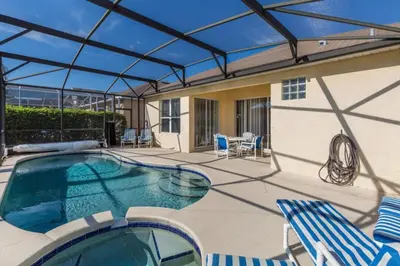 a patio with a swimming pool with chairs and a house at Windsor Palms Villa: Pool & Close to Disney in Kissimmee