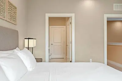 a bedroom with a white bed and a door to a hallway at 7562 Magic Village: 4 Suítes, 8 Hóspedes, Apenas 8 Minutos da Disney! in Orlando