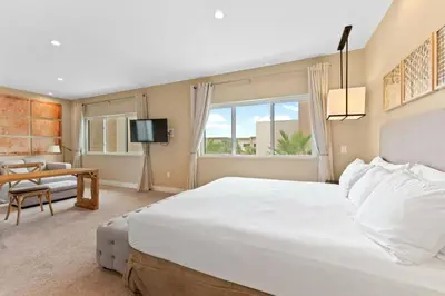 a bedroom with a large white bed and a living room at 7562 Magic Village: 4 Suítes, 8 Hóspedes, Apenas 8 Minutos da Disney! in Orlando