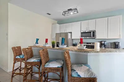 a kitchen with white cabinets and bar stools at 7774 Basnett Circle in Kissimmee
