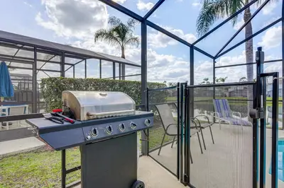 a grill on a patio with a table and chairs at 9 Mi to Disney Home with Pool Table and Water Views! in Kissimmee