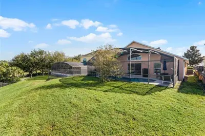 a house on a grassy yard with a fence at Ultimate family resort home with incredible sunset views, 4 miles from Disney! in Kissimmee