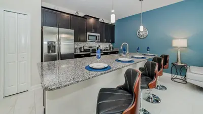 a kitchen with a counter with chairs and a refrigerator at JLT3076 Storey Lake Resort Vacation Townhome in Kissimmee