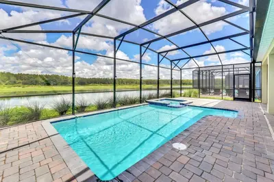 an indoor pool in a glass house with a view of a river at Serenity Lakeview Retreat Stunning Water Views, No Rear Neighbors, Private Pool, Game Room Star Wars Cinema in Kissimmee