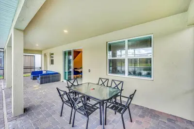 a patio with a glass table and chairs at Serenity Lakeview Retreat Stunning Water Views, No Rear Neighbors, Private Pool, Game Room Star Wars Cinema in Kissimmee