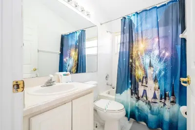 a bathroom with a toilet and a shower curtain at Near Disney with Pool and BBQ 4BD Single House in Kissimmee