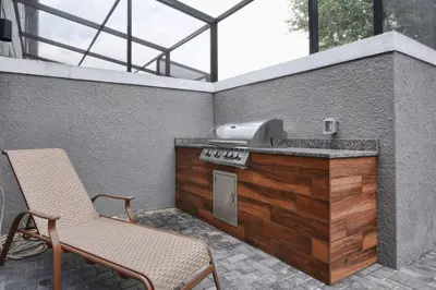 a outdoor kitchen with a chair and a grill at Beautiful 4BD home Themed Pool and Grill 4417 in Kissimmee