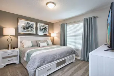 a bedroom with a bed and a tv and a window at Beautiful 4BD home Themed Pool and Grill 4417 in Kissimmee