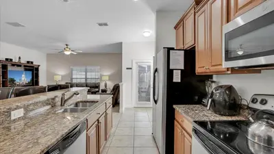 a kitchen with wooden cabinets and a black refrigerator at CAT8967 in Kissimmee