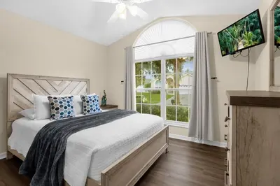 a bedroom with a bed and a large window at Spacious Disney Retreat with pool & parking in Kissimmee