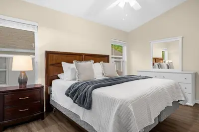 a white bedroom with a large bed and a window at Spacious Disney Retreat with pool & parking in Kissimmee