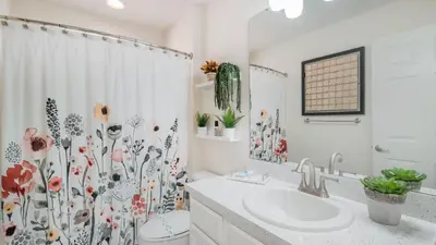 a bathroom with a sink and a shower curtain with flowers at LDK2787 in Kissimmee