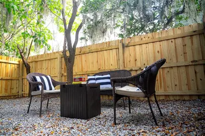 three chairs and a table in front of a fence at Historic Orlando Casita Love Apt A with backyard in Orlando