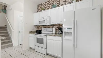 a kitchen with white cabinets and a refrigerator at Spacious Family Townhouse Sleeps 8 in Kissimmee
