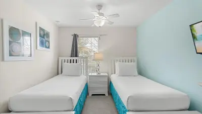 two beds in a room with white walls and a window at Spacious Family Townhouse Sleeps 8 in Kissimmee