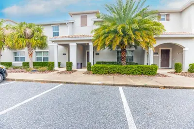 a house with palm trees in front of a street at Amazing Townhouse TVPM in Kissimmee