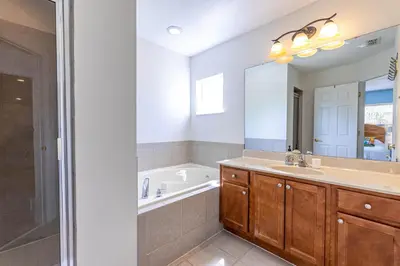 a bathroom with a tub and a sink and a mirror at Gorgeous Villa with Pool and Spa in Kissimmee