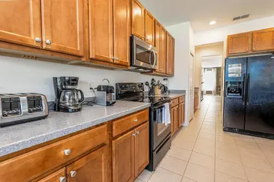 a kitchen with wooden cabinets and a black refrigerator at Gorgeous Villa with Pool and Spa in Kissimmee