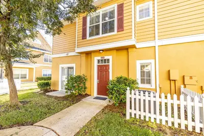 a yellow house with a white fence in front of it at Spectacular townhouse with themed room in Kissimmee
