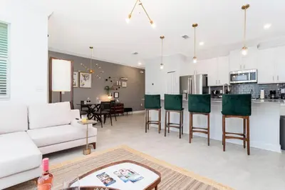 a living room with a white couch and a kitchen at La Vita E Bella 4 Bedroom Storey Lake Condo in Kissimmee