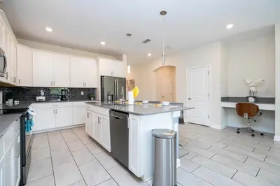 a large kitchen with white cabinets and a counter at Stunning Game Room & Pool Jacuzzi Storey Lake 2799 in Kissimmee