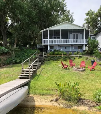 a house with red chairs in front of it at Lakefront with Dock on Private Lake Florence near Montverde Academy in Montverde