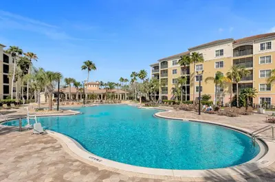 a swimming pool in a resort with palm trees and buildings at WorldQuest Resort in Orlando