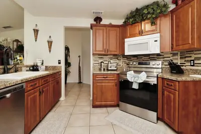 a kitchen with wooden cabinets and a white microwave at Ideal for Couples or Families looking for a Vacation Home with Private Pool and Yard in Kissimmee