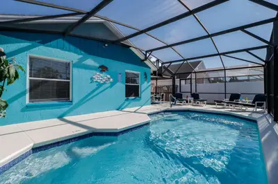 a swimming pool with a blue building with a glass roof at Ideal for Couples or Families looking for a Vacation Home with Private Pool and Yard in Kissimmee