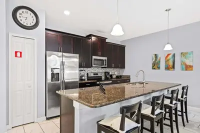 a kitchen with stainless steel appliances and a clock on the wall at Spacious 4BR Townhome with Pool at Storey Lake in Kissimmee