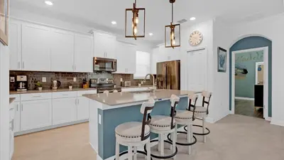 a kitchen with white cabinets and a island with bar stools at PLW4277 in Kissimmee