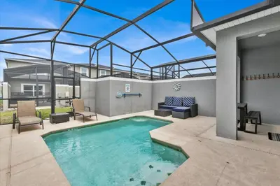 a swimming pool in a patio with chairs and a table at QTS4361 in Kissimmee