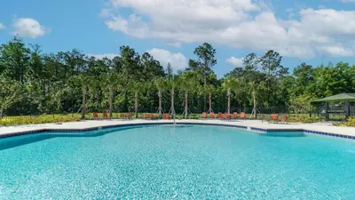 a swimming pool at a resort with chairs and trees at NRL4543 in Kissimmee
