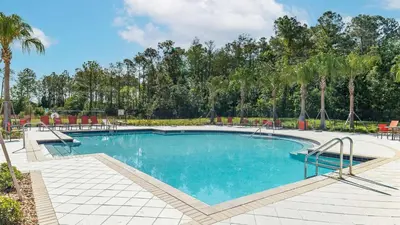 a swimming pool with tables and chairs and palm trees at NRL4543 in Kissimmee