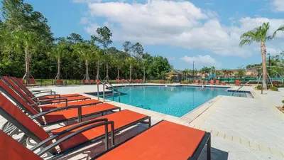 a swimming pool with red chairs and palm trees at NRL4543 in Kissimmee