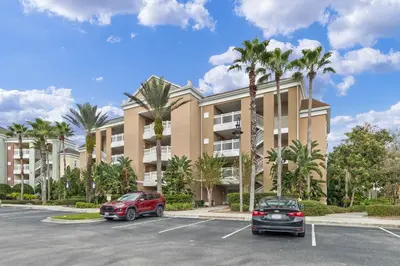 two cars parked in a parking lot in front of a building at AQ0401 Villas North Charm in Orlando
