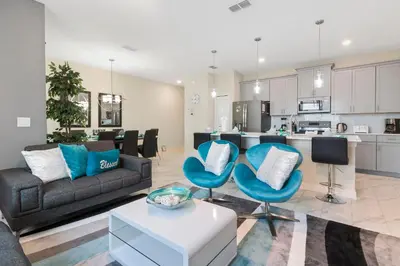 a living room with a couch and chairs and a kitchen at Villa Kerpen - Storey Lake in Kissimmee