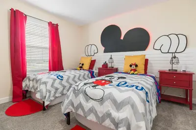 two beds in a bedroom with red curtains at Villa Kerpen - Storey Lake in Kissimmee